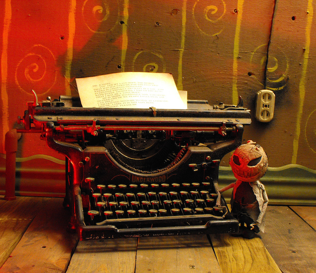 scary image of Underwood typewriter with scary-looking figurine next to it